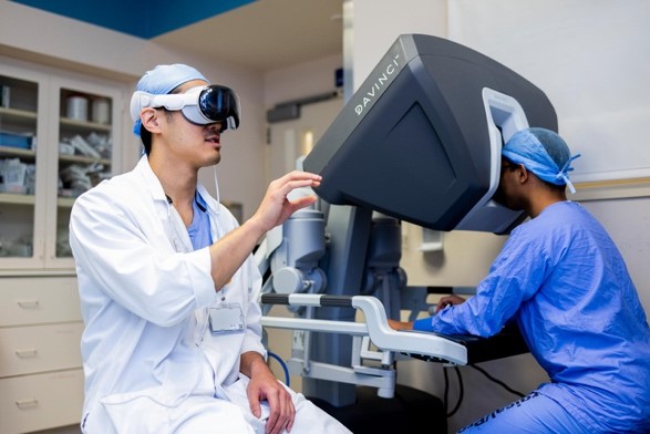 Clinician using HoloMedicine XR glasses beside a da Vinci console